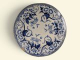 a blue and white plate with flowers and vines on it