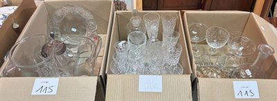 Plusieurs cartons contenant de la verrerie sont empilés sur une table dans une pièce.