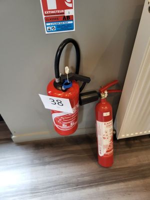 un extincteur posé à côté d'une bouche d'incendie sur le sol