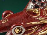a red and gold sculpture of a fish on a green surface