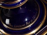 a close up of a blue and gold vase on a table