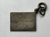 a close up of a metal tag on a white surface