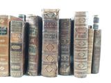 several old books are lined up on a shelf in a row