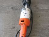 une perceuse électrique orange et blanche posée sur une table en bois