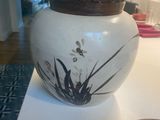 a white vase with a brown lid sitting on a table