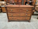 une commode en bois avec de nombreux tiroirs et des chaises à l'arrière-plan