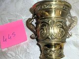 a gold vase on a table with a note attached to it