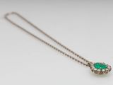 a close up of a necklace with a green stone on it