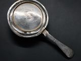 an old silver plate with a spoon on a black surface