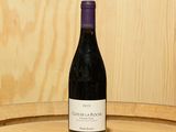 a bottle of wine sitting on top of a barrel