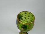 a green and gold glass cup with a gold rim