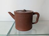a brown tea pot sitting on a glass shelf