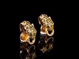 une paire de boucles d'oreilles dorées en forme de léopard sur un fond noir