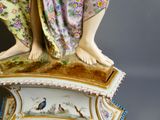 une figurine représentant une femme tenant un oiseau, posée sur une table