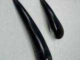 une paire de grandes dents noires sur une surface blanche