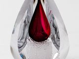 a glass vase with a red tear inside of it