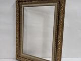 an old gold framed mirror with a white wall behind it