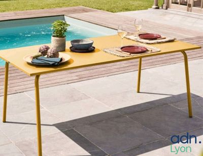 une table jaune avec des assiettes dessus, près d'une piscine
