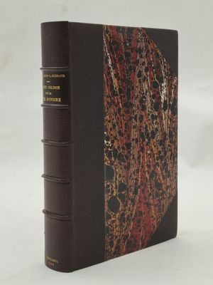 un livre marron à la couverture rouge et noire posé sur une surface blanche