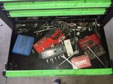une boîte à outils verte remplie d'outils, posée par terre