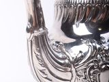 a silver tea pot on a stand with a bird on it