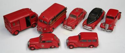 cinq petites voitures rouges et un bus posés sur une surface blanche
