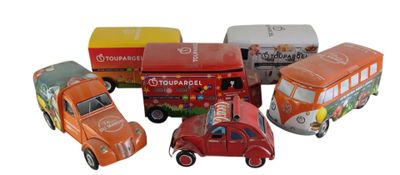 Plusieurs petites voitures et camions sont alignés sur une surface blanche