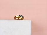 un gros plan d'une bague en or et en argent posée sur un bloc de marbre