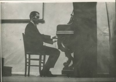 black and white photograph of a man sitting at a piano