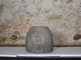 un vase en pierre posé sur une table devant un mur de briques