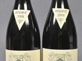 two bottles of red wine sitting next to each other on a table
