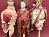 three antique dolls are lined up against a red background