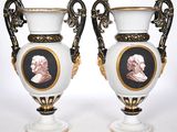 two white vases with black and gold trims with a portrait of a man and a woman on them