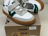des baskets blanches et vertes à velcro, avec des semelles en velcro, posées sur une boîte en carton