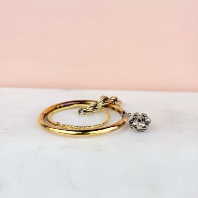 a pair of gold rings with diamonds on a marble surface