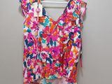 a floral top hanging on a hanger against a wall