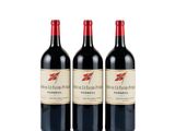 three bottles of red wine sitting next to each other on a white surface