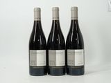 three bottles of red wine sit on a white surface