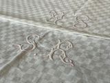 two monograms on a bed sheet with a checkered pattern