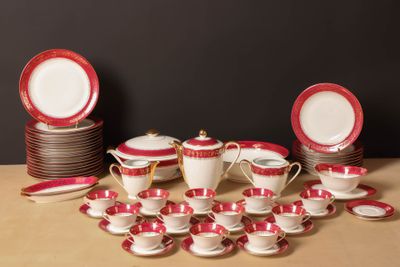 a lot of red and white dishes and cups on the table
