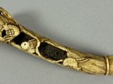 an old carved horn with a skull and two children on it