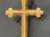 gold cross on a black surface with a chain hanging from it ' s end