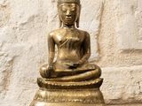 statue d'un Bouddha assis sur une table devant un mur de pierre