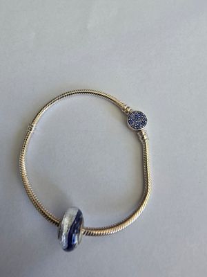 a close up of a silver bracelet with a blue bead