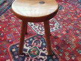 un petit tabouret en bois posé sur un tapis dans un salon