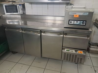 plan de travail en acier inoxydable dans une cuisine professionnelle équipée d'un micro-ondes et d'un four