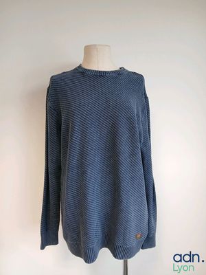 a blue sweater on a mannequin stand against a white wall
