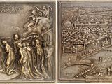 two metal plaques depicting a scene of a city and a man on a horse