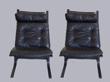 une paire de fauteuils de salon en cuir noir avec des pieds en métal noir