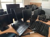 a lot of computer monitors and keyboards on the desk